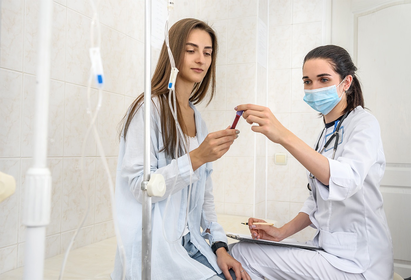 Patient in hospital with doctor holding clipboard