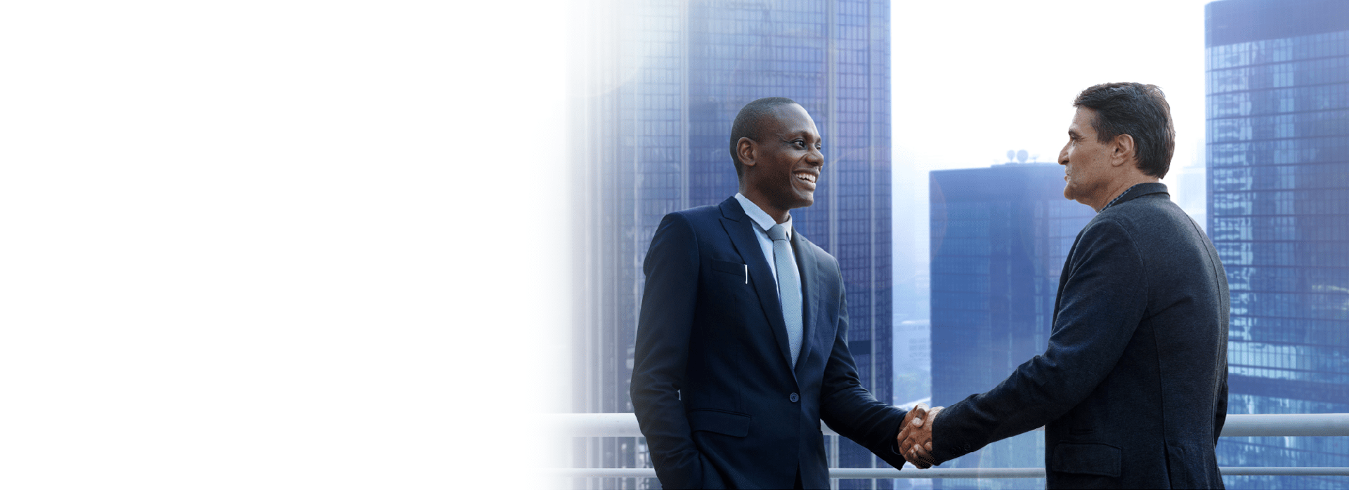 two men in suits shaking hands atop building