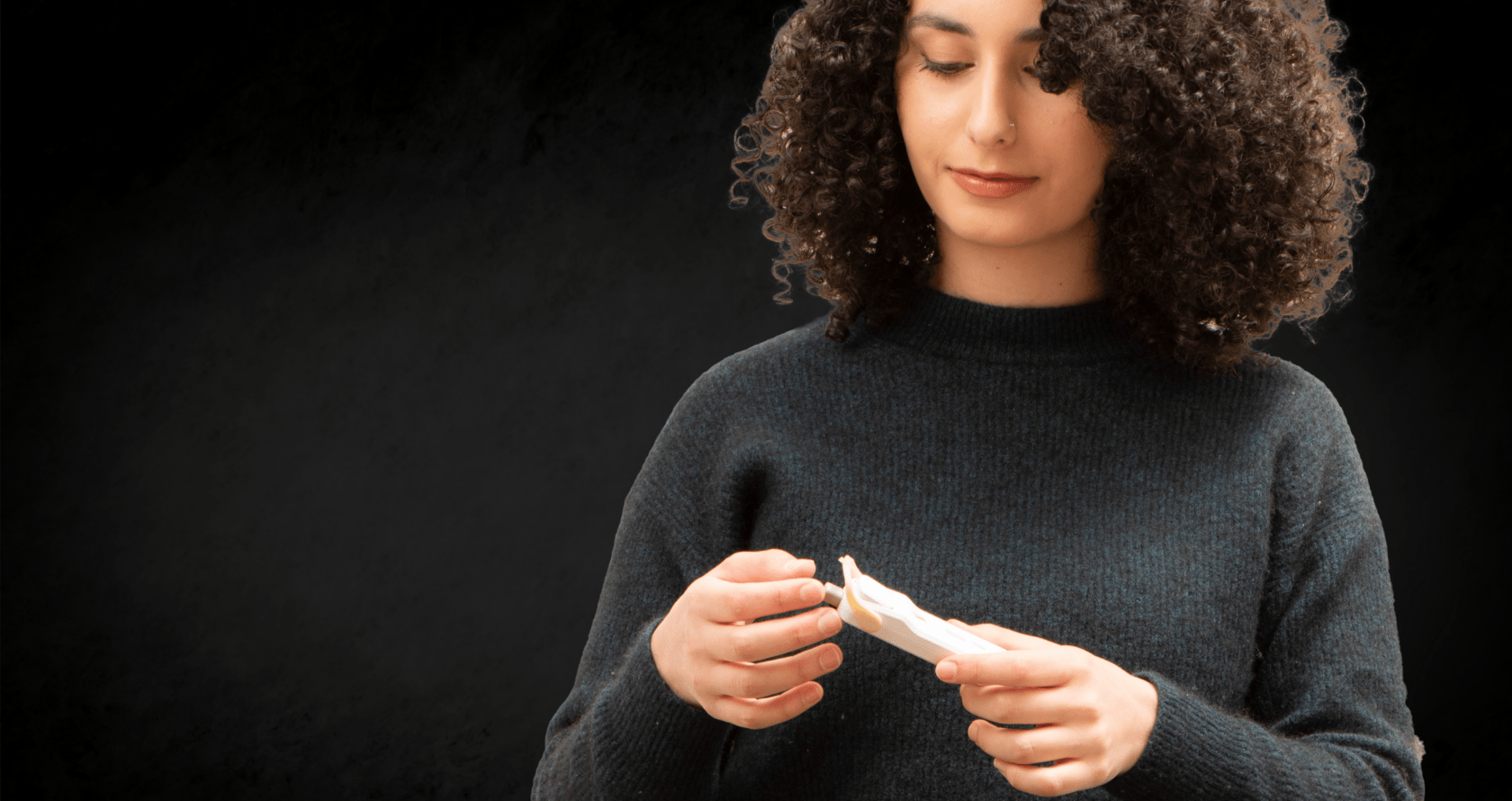 Woman in front of black background, holding diagnostic cassette